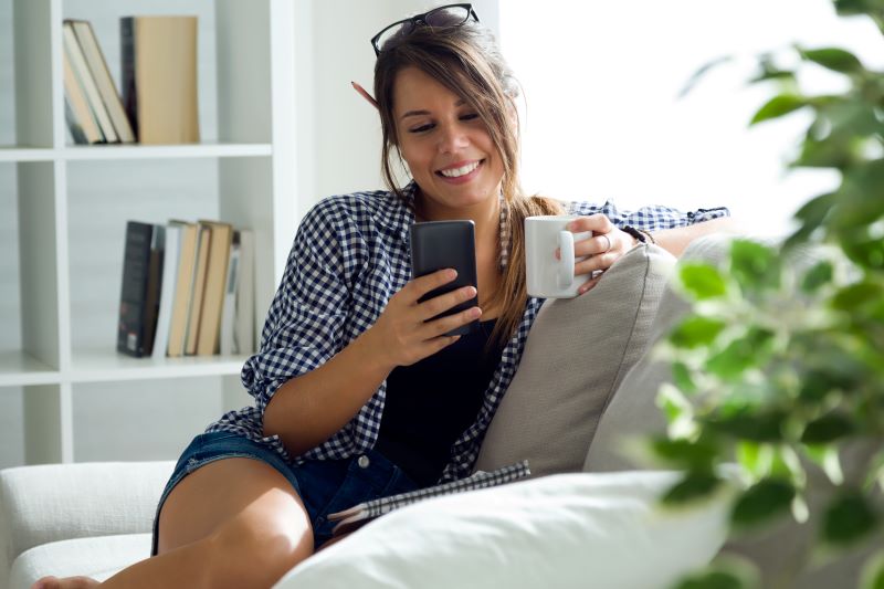 schoene-junge-frau-die-zu-hause-ihren-handy-verwendet schoene-junge-frau-die-zu-hause-ihren-handy-verwendet
